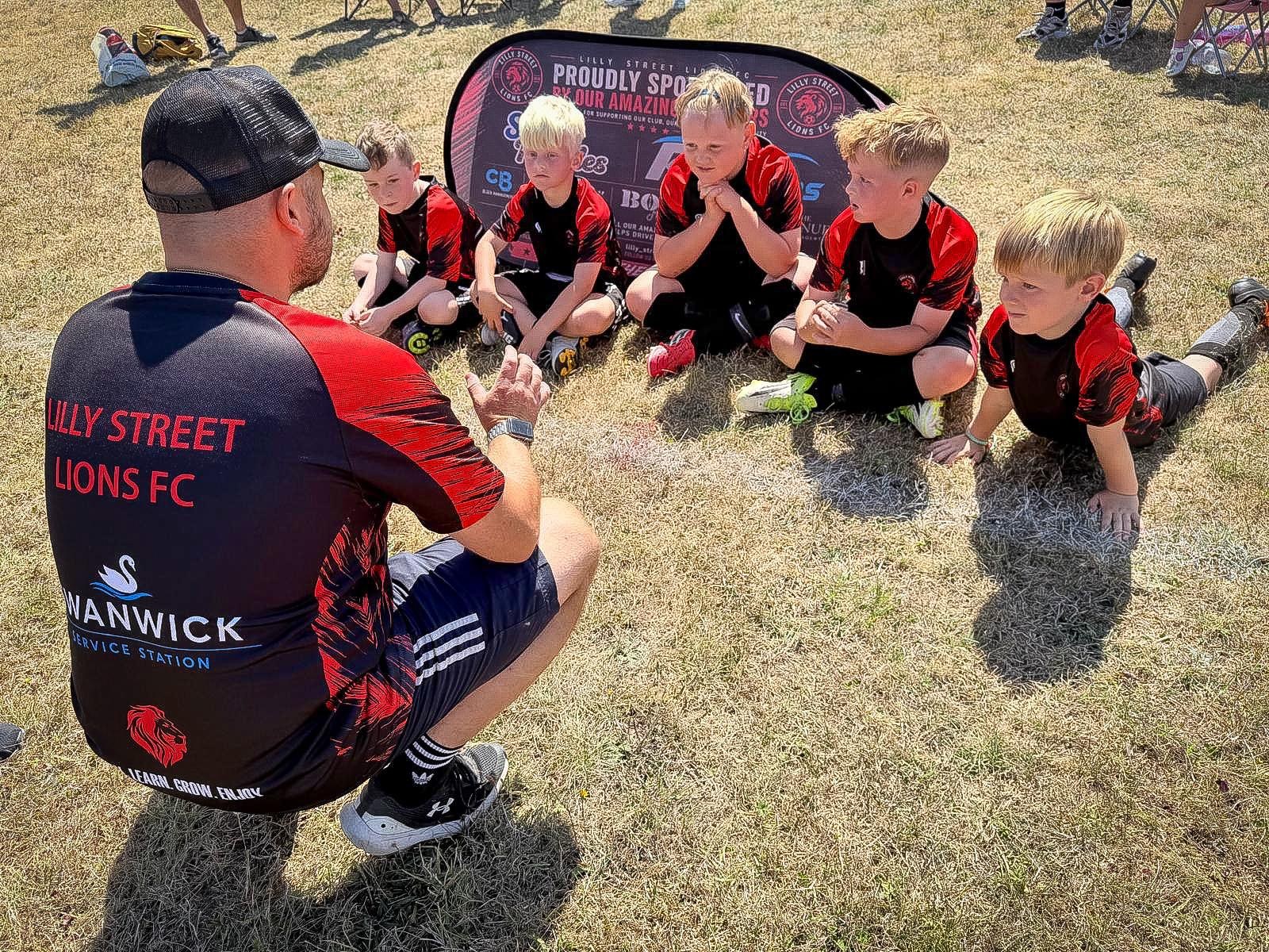 Coach speaking with Under-8 players during a team session